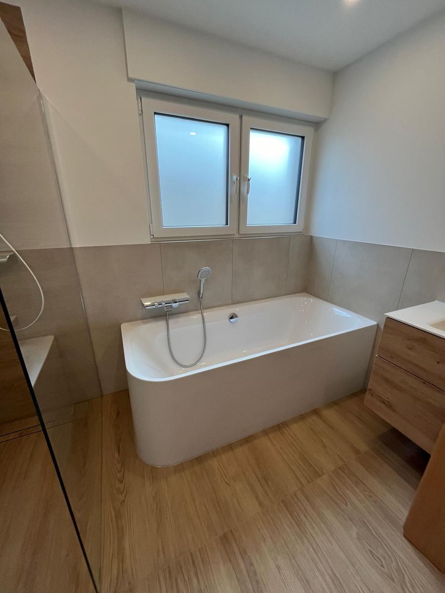 Freistehende Badewanne vor Fliesen in Steinoptik